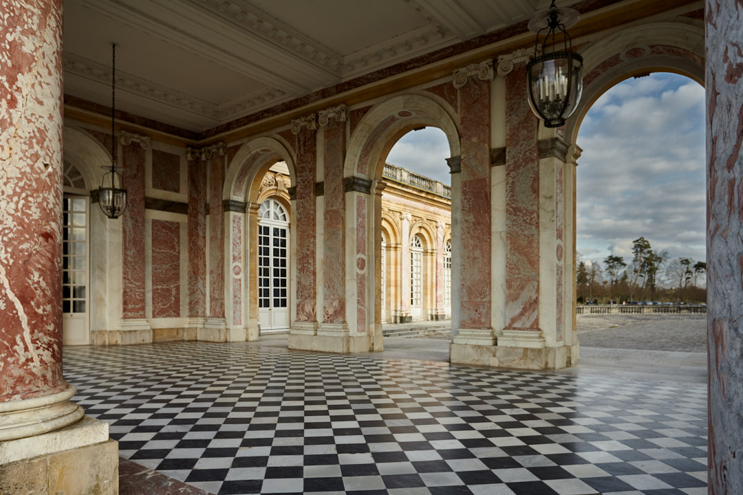 An open colonnade where architecture and nature meet. The marble columns frame the gardens beyond, while the geometry of the floor draws the eye through the space. The repetition of arches, columns and squares creates a precise architectural rhythm, softened by the irregular patterns of the marble and the landscape beyond. What interests me here is the conversation between the two: the order imposed by architecture and the less predictable forms of nature. For a moment, neither dominates. Stone and garden become parts of the same composition, connected by light, pattern and perspective.